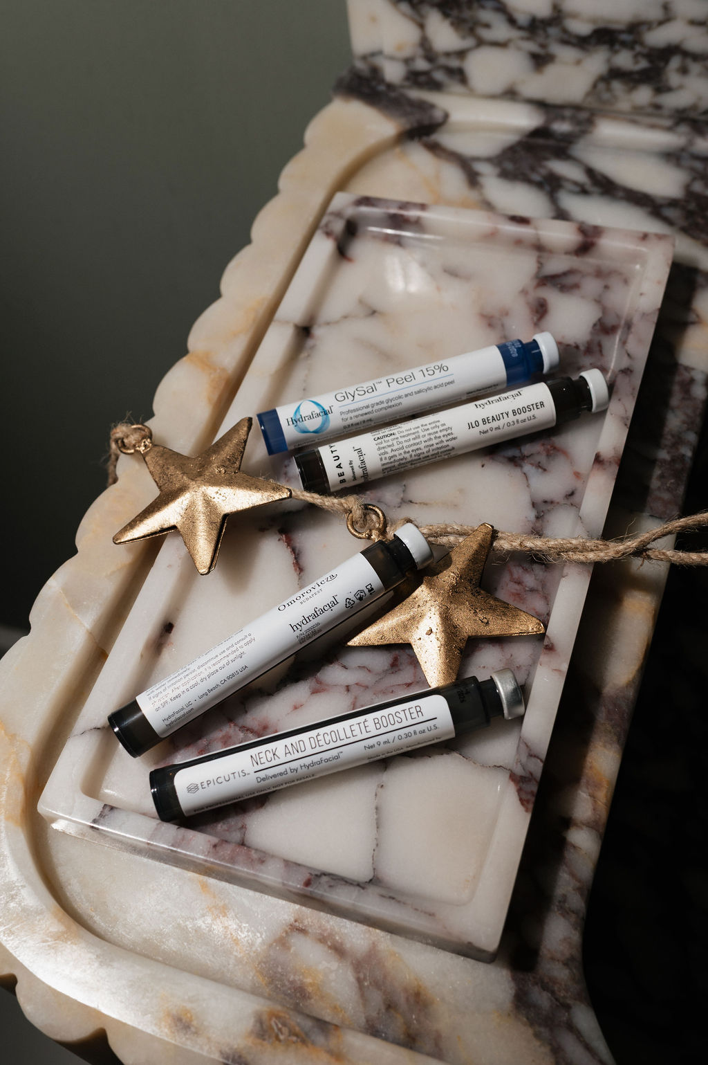 HydraFacial and Epicutis skincare booster vials on marble tray with gold star ornaments