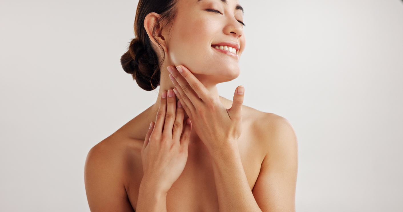 A woman gently massaging her neck and jawline, showcasing glowing skin in a skincare self-care routine.