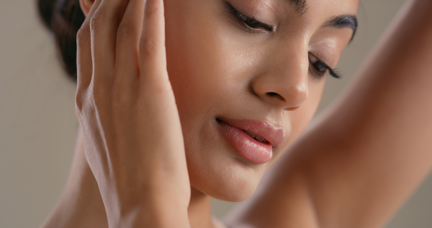 Close-up of a woman touching her cheek, showcasing smooth skin and natural makeup for skincare or beauty routine.