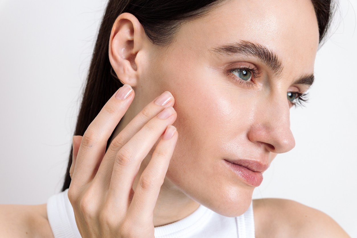 Close-up of a woman touching her cheek, highlighting glowing skin and healthy skincare results