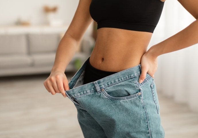 Unrecognizable Black Lady Showing Abdominal Muscles Wearing Oversized Jeans Indoor